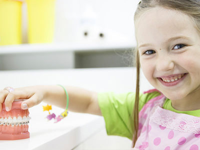 Girl holding to teeth mold with braces
