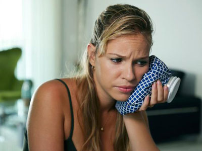 Woman icing her cheek from tooth pain.