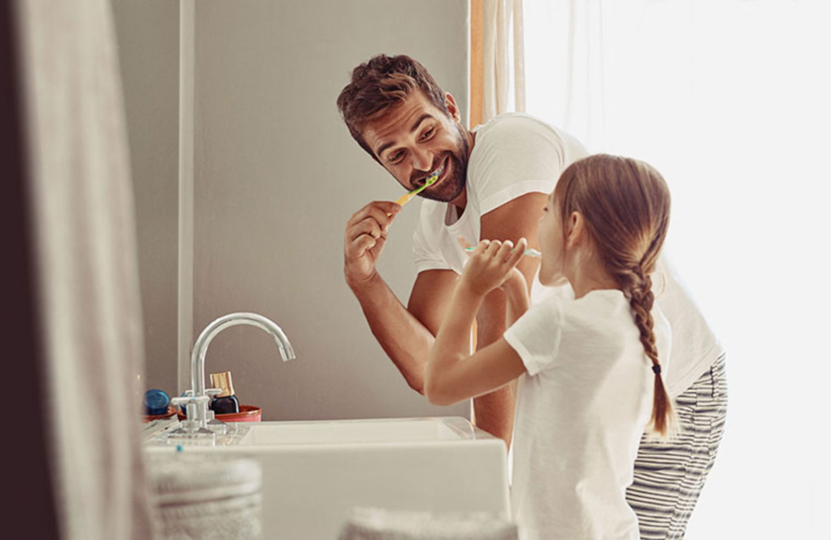 Father and daughter brushing teeth