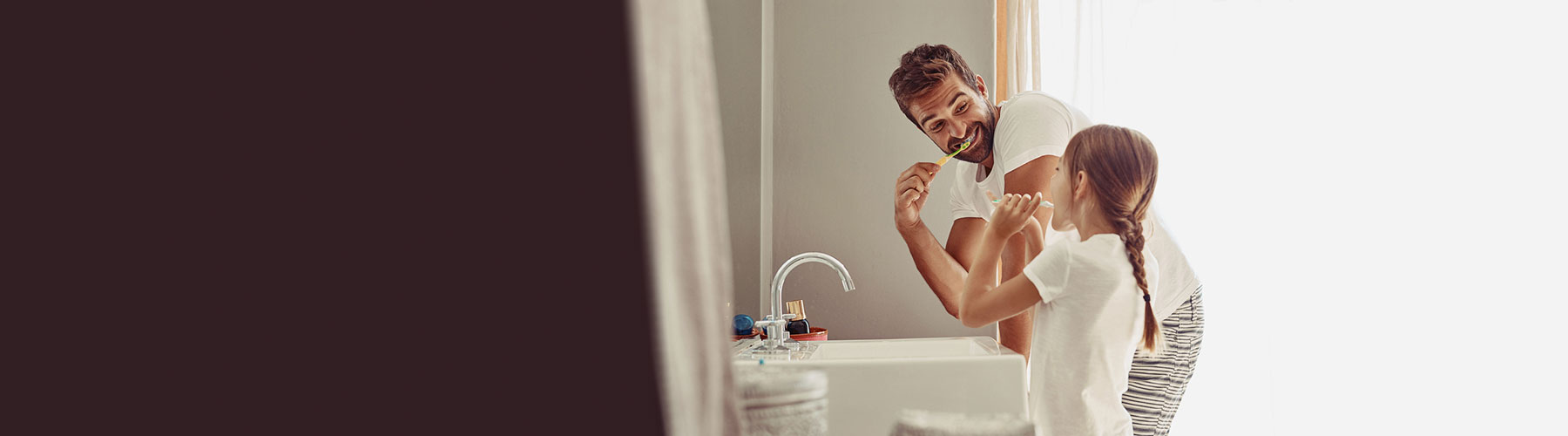 Father and daughter brushing teeth